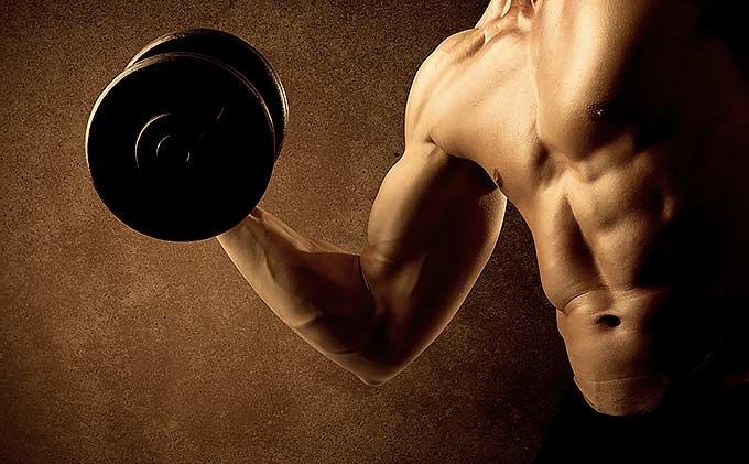 A guy on a brown background using dumbbell for a biceps exercise