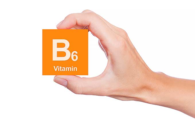 An orange vitamin B6 object, hold by a hand